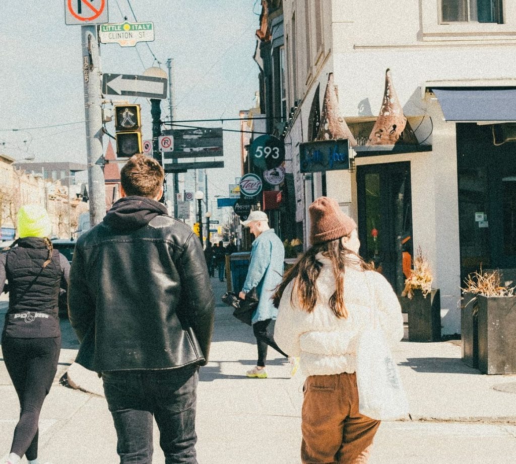 pedestrians walk across the street in Toronto’s Little Italy 