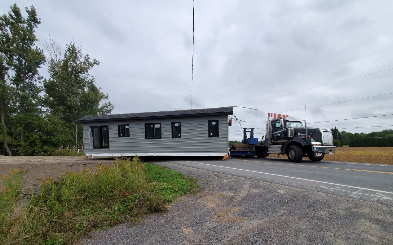 Photo of home built by College la Cite students arriving at lot on trailer.