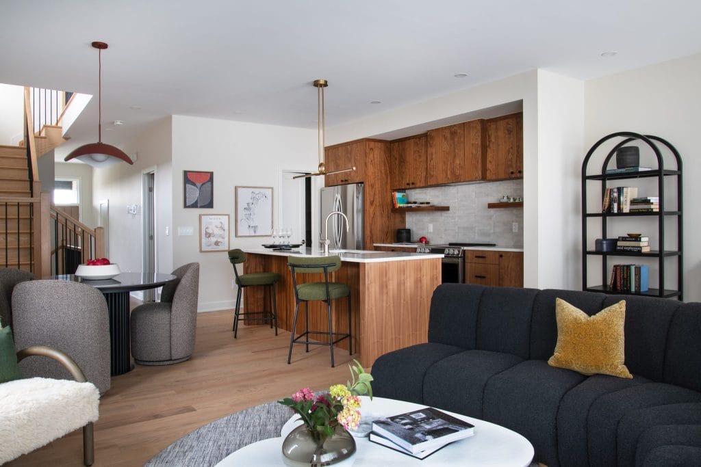 Open-concept Driftwood townhome by Uniform Urban Developments, showing the kitchen (with its wood cabinets) and dining area from the living room