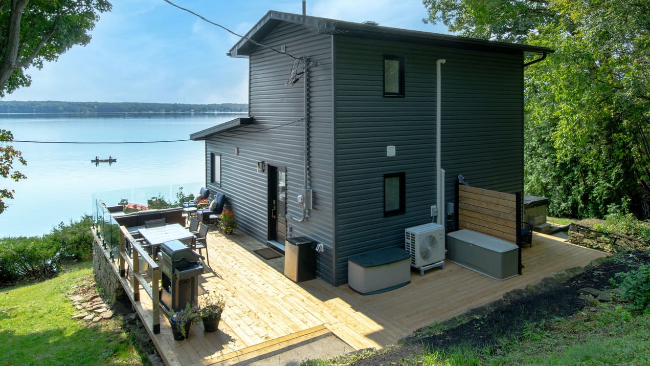 back of a home looking out over a river with a deck around it by amsted design-build showing outdoor spaces that fit