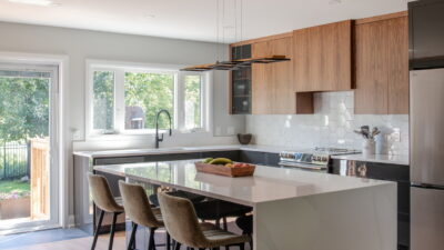 kitchen renovation by Amsted Design-Build showing a mix of dark and lighter wood cabinets and an island with seating for three.