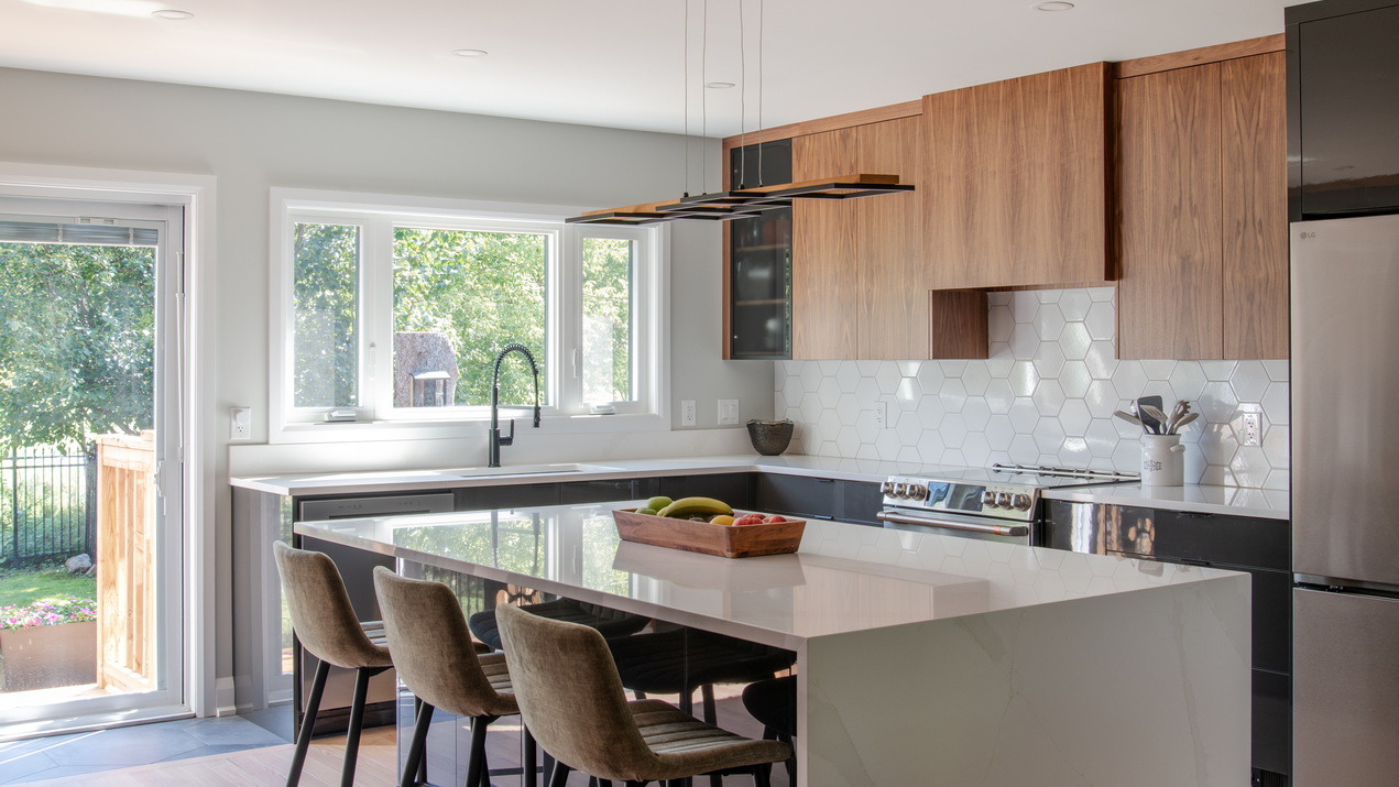 kitchen renovation by Amsted Design-Build showing a mix of dark and lighter wood cabinets and an island with seating for three.