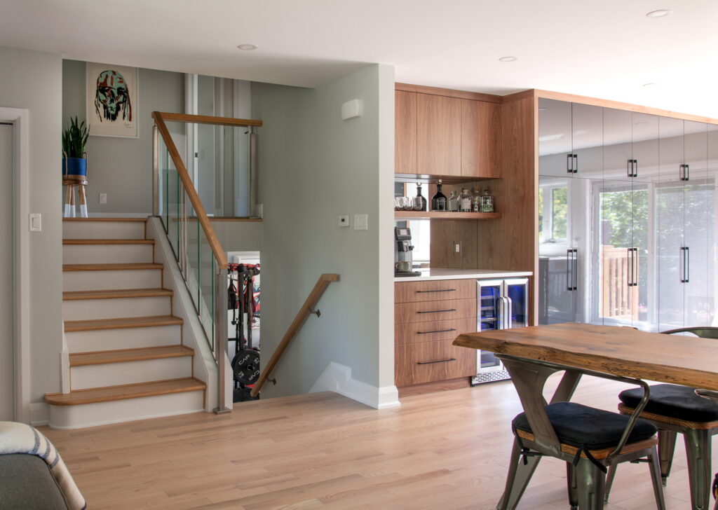 open-concept main floor in the renovation of a split-level home, showing part of the dining table, a drinks station, pantry wall and the stairs