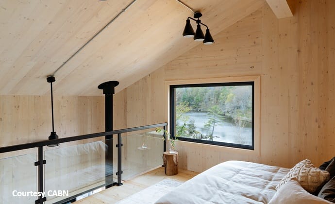 Cabin loft bedroom open to below with cross-laminated timber walls and roof