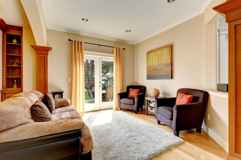 Cozy living room area with comfortable sofa, chairs and soft rug. View of glass door to the backyard