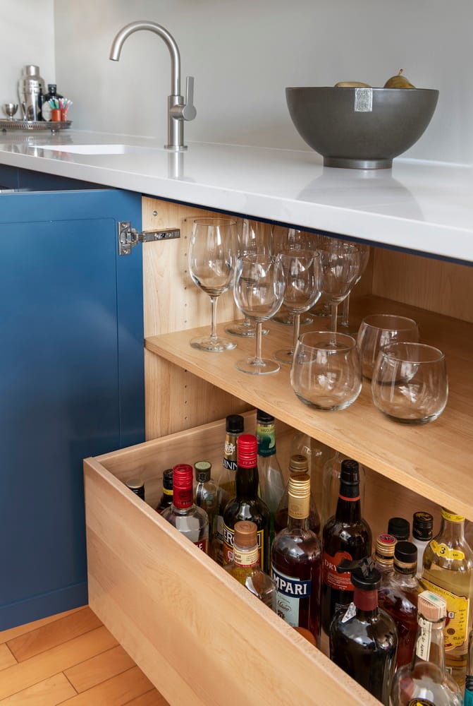 closeup of an open kitchen cabinet door showing pullout storage drawers inside