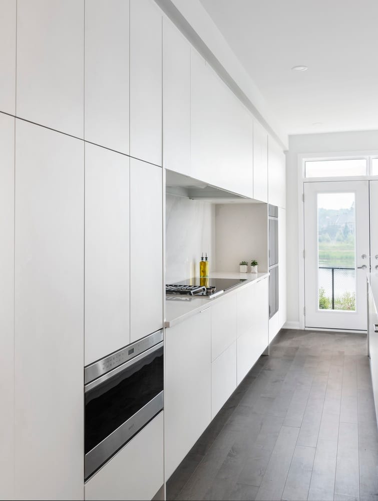 contemporary white kitchen showing flat cabinet doors in a clean-lined, minimalist design with no handles