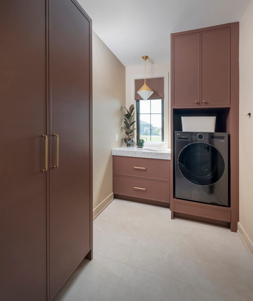 main-floor laundry room with an all-in-one washer-dryer machine and built-in cabinetry, sink and window