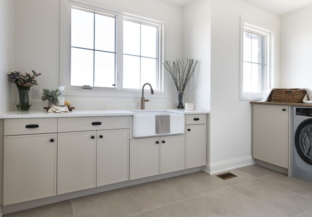 neutral laundry room with thin shaker cabinets in a light beige and large-format floor tile