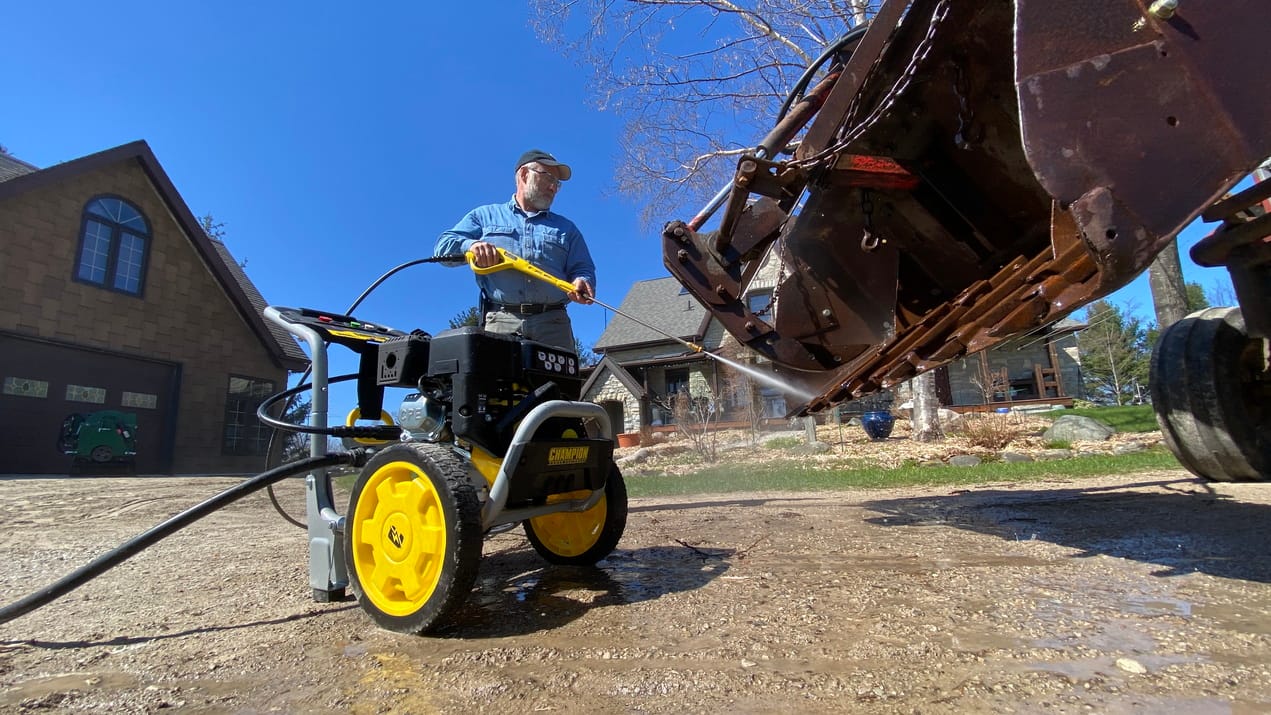 a man pressure washes yard equipment