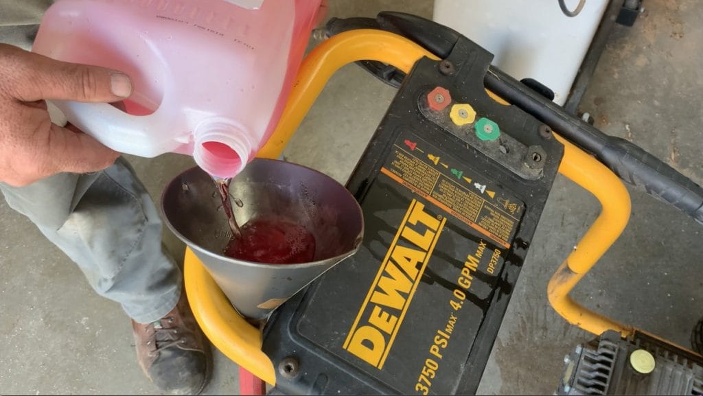 closeup photo of a man pouring antifreeze into a funnel for a pressure washer