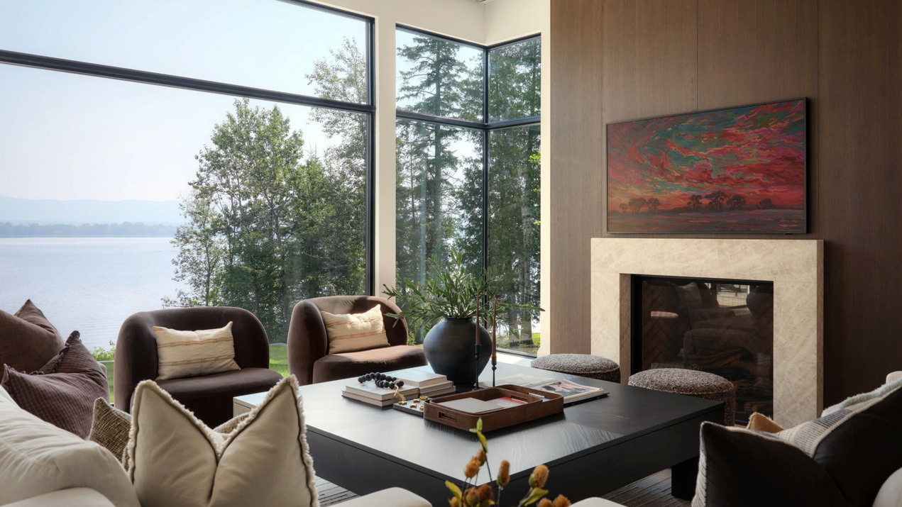 contemporary living room of a waterfront custom home, with floor-to-ceiling windows and fireplace