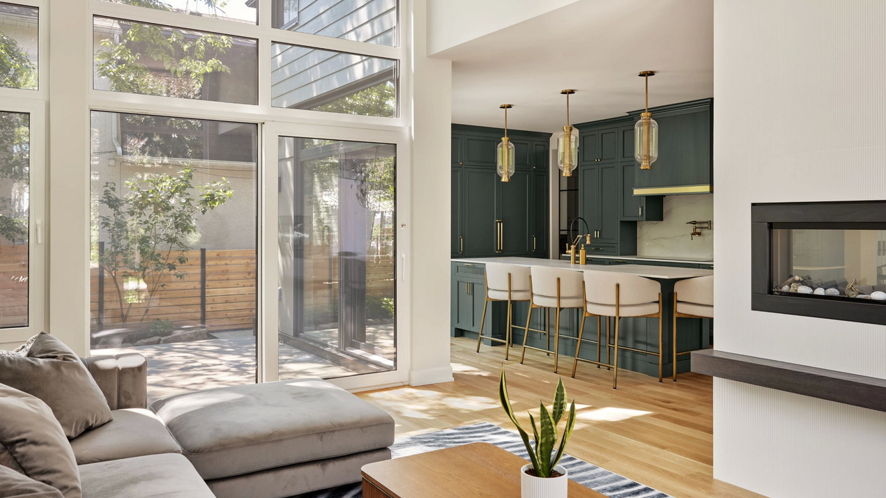 great room looking into the kitchen of a custom home with floor-to-ceiling windows connecting the backyard