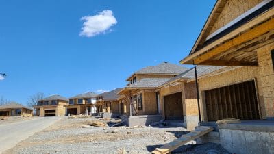 photo of a residential construction site showing single-family homes under construction on a curved street