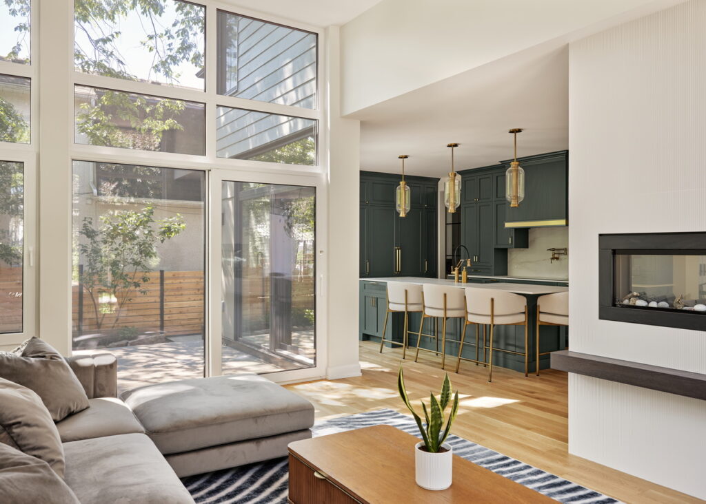 interior of a custom home by RND Construction looking from the living room into the kitchen and showing glass walls overlooking the courtyard