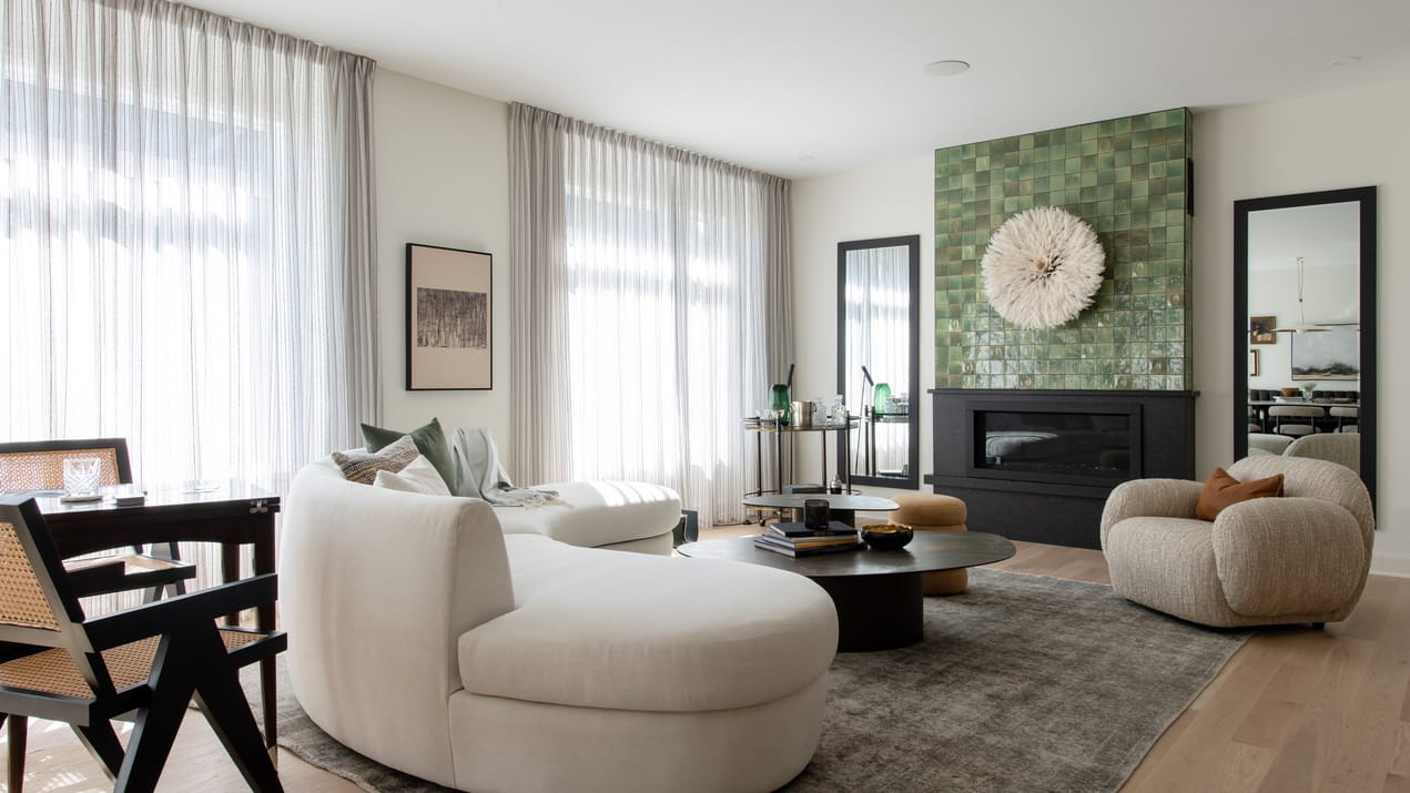open-concept single-family home looking from the kitchen island to the living room with its curved white sofa and linear fireplace.