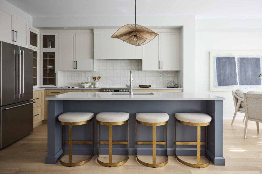 photo of the open-concept kitchen in the samira townhome model by tamarack homes. It features a blue island, white upper cabinets and wood lower perimeter cabinets