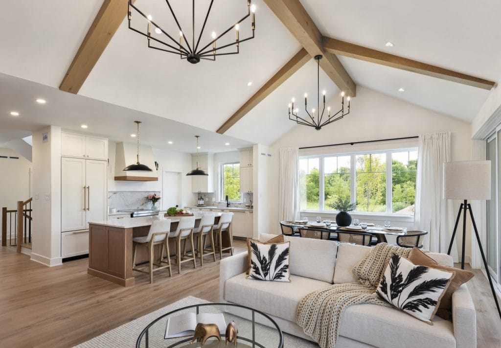 open-concept main floor of Watercolour Westport’s model home, featuring a vaulted ceiling with beams, kitchen, dining room and living room done in soft neutrals
