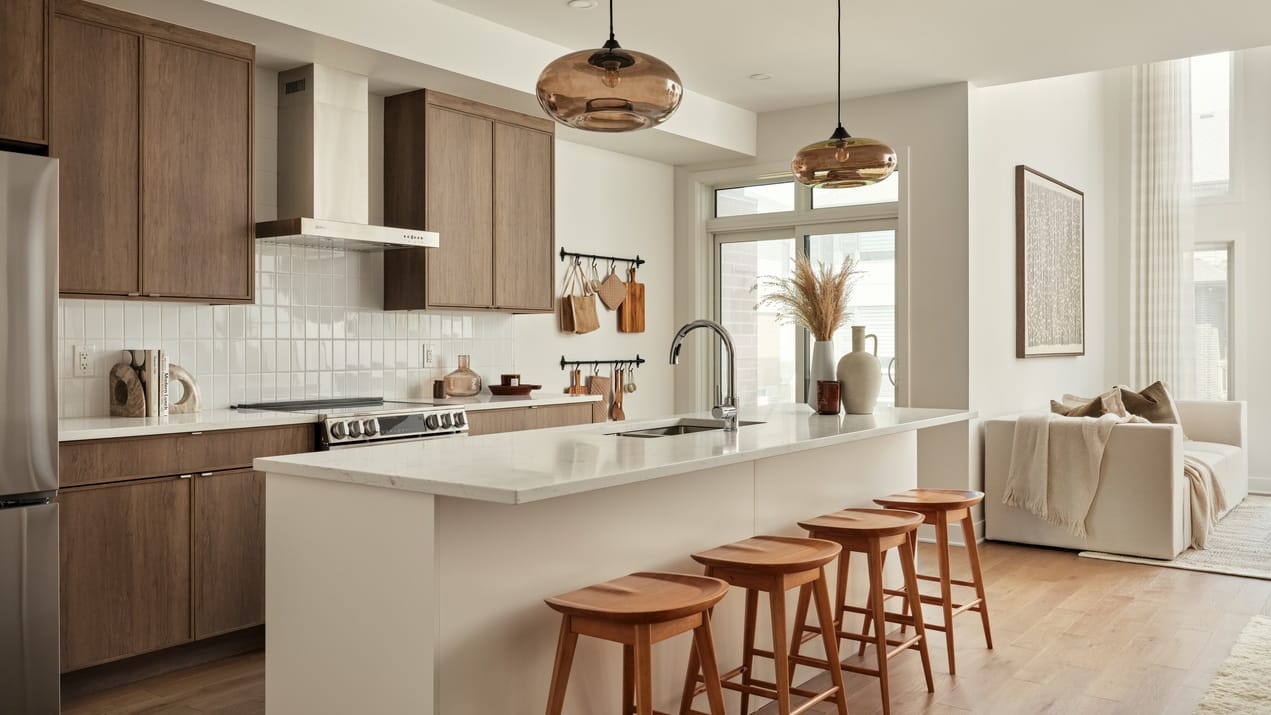 contemporary kitchen in the Endeavour model by Urbandale at Kanata Lakes. Features a white island, wood perimeter cabinets and a stainless-steel hood vent