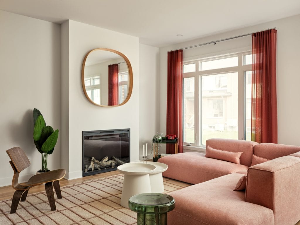 living room of the Atlantis II townhome model by Urbandale Construction at Kanata Lakes with electric fireplace and soft orange sectional sofa.