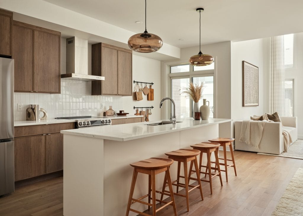 contemporary kitchen in the Endeavour model by Urbandale at Kanata Lakes. Features a white island, wood perimeter cabinets and a stainless-steel hood vent